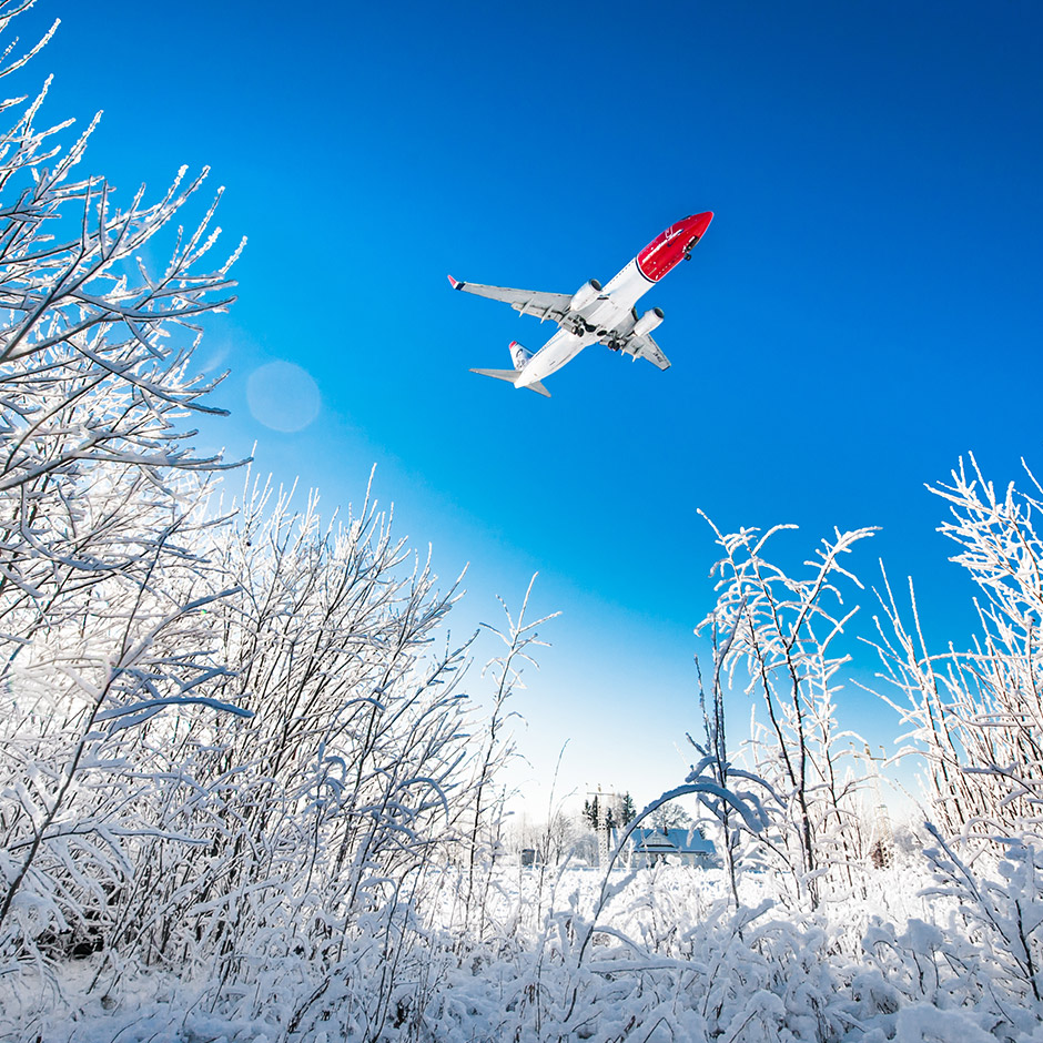 Un avion de la compagnie Norwegian volant au dessus d’une étendue de neige